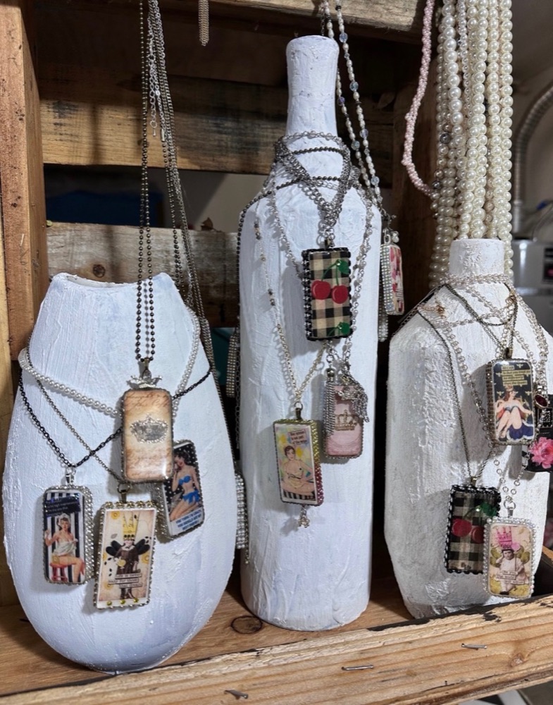 Handmade pendant necklaces displayed on white plaster bottles