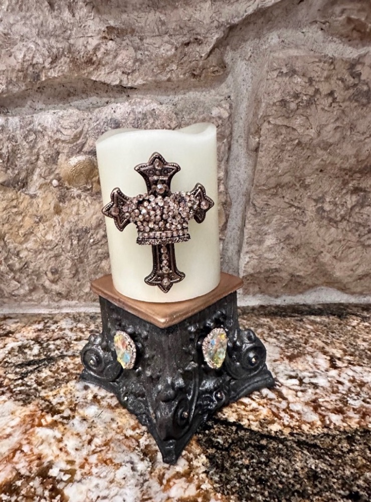 Cream candle with crystal cross on an ornate black pedestal